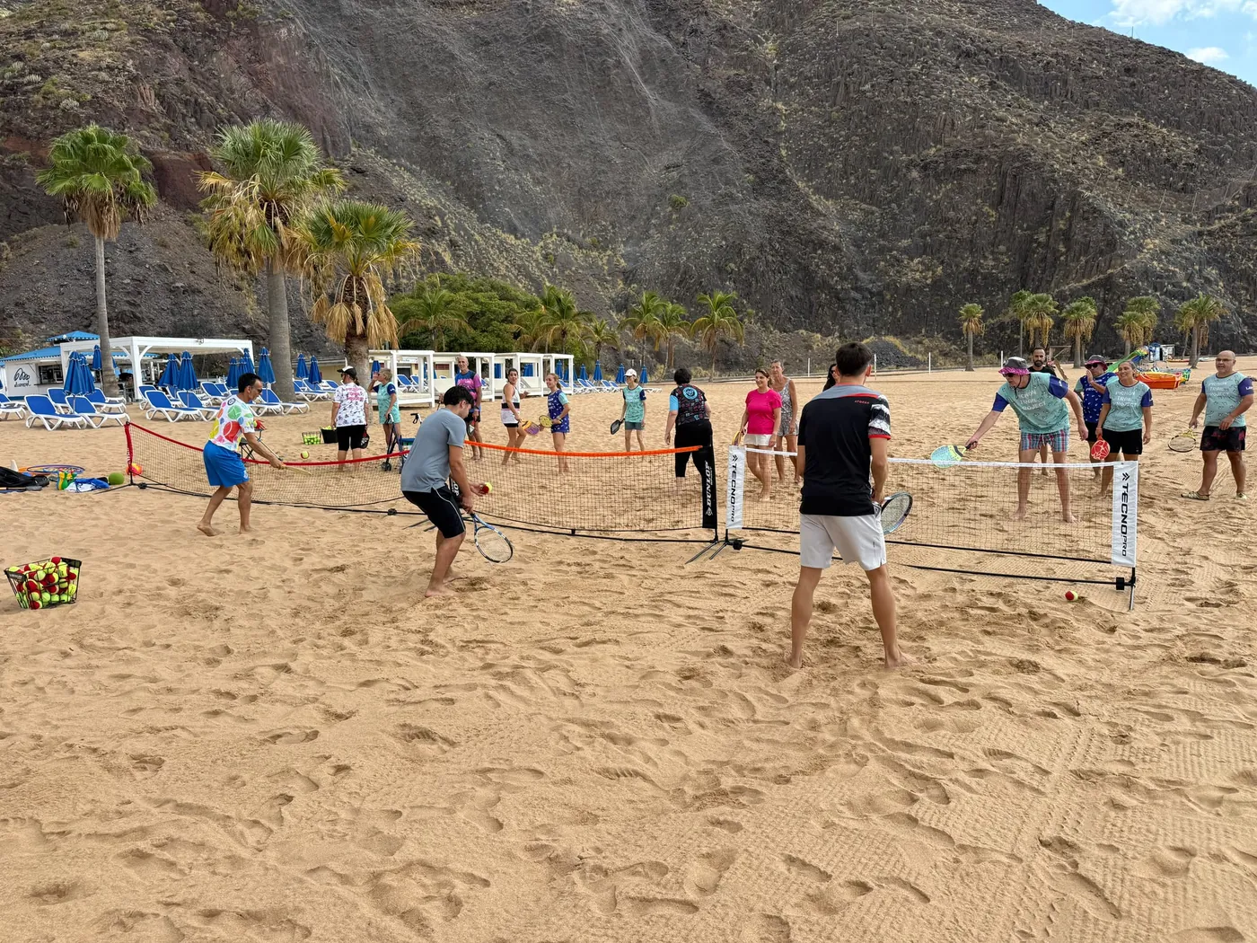 Participantes practicando tenis playa durante una sesión conjunta de EMpláyate y EMbolas en Las Teresitas
